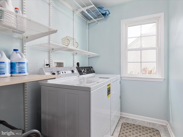 laundry area featuring light tile patterned floors, laundry area, washing machine and dryer, and baseboards