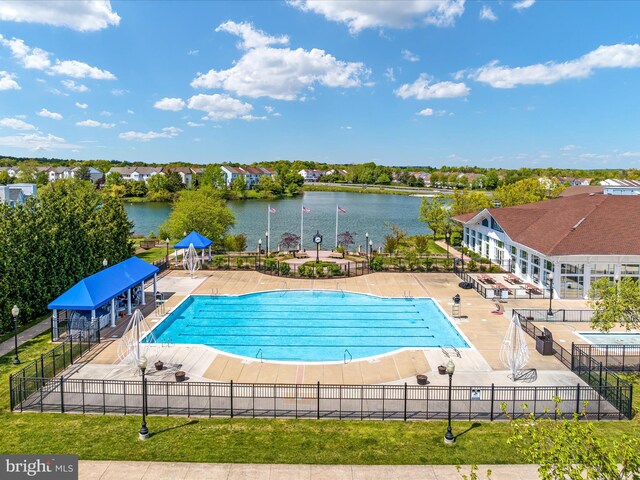 pool featuring fence, a patio, and a water view
