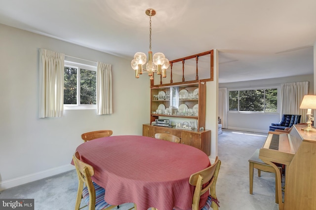 dining space featuring light colored carpet, baseboards, plenty of natural light, and a chandelier