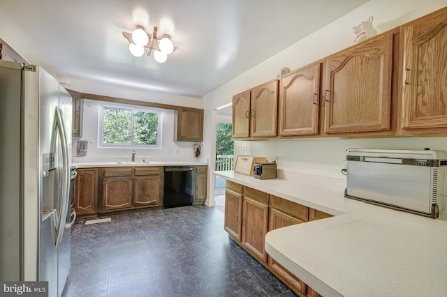 kitchen with brown cabinetry, black dishwasher, stainless steel refrigerator with ice dispenser, light countertops, and a sink