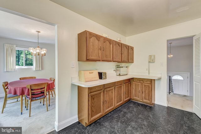 kitchen featuring brown cabinets, baseboards, a chandelier, and light countertops