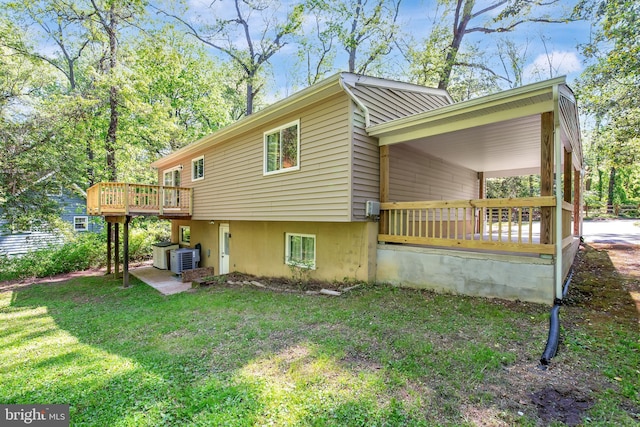 rear view of property with central air condition unit, a wooden deck, and a yard
