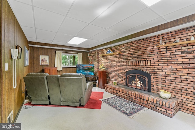 living room with a fireplace, wood walls, brick wall, and a paneled ceiling