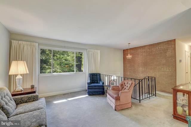 carpeted living room featuring baseboards and brick wall