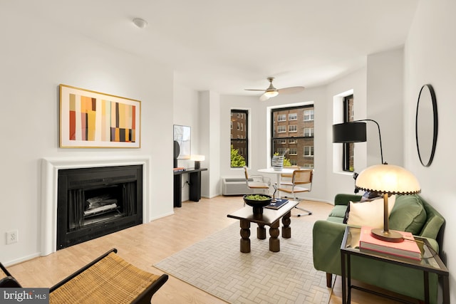 living room featuring a ceiling fan, wood finished floors, and a fireplace