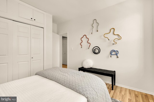 bedroom with a closet, light wood-style flooring, and baseboards