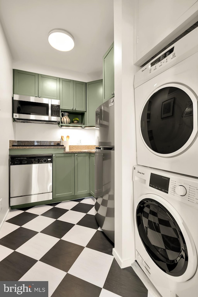 clothes washing area with stacked washer / dryer, light floors, and baseboards