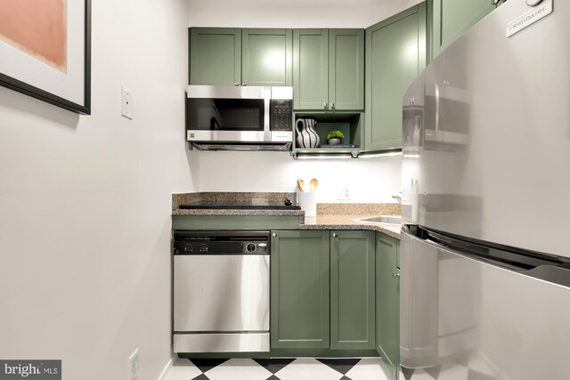 kitchen with green cabinetry, appliances with stainless steel finishes, and tile patterned floors