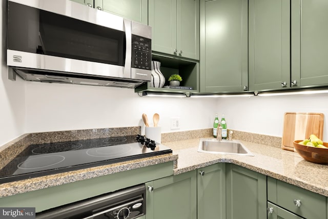 kitchen featuring stainless steel microwave, green cabinets, and black electric stovetop
