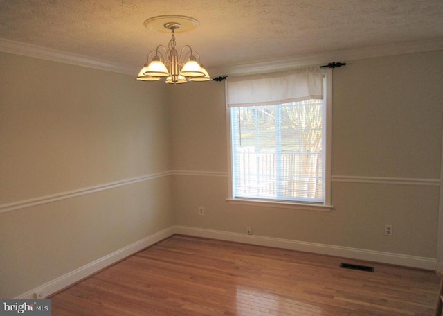 spare room with wood finished floors, visible vents, baseboards, a chandelier, and a textured ceiling