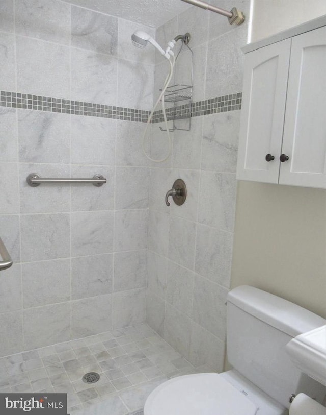 bathroom with a tile shower and toilet