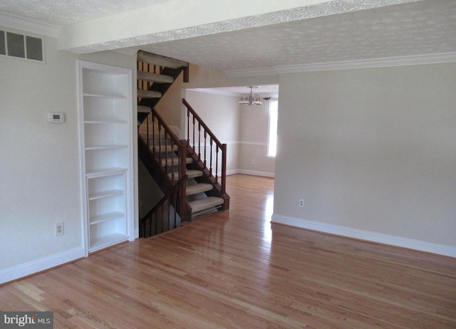 interior space with wood finished floors, visible vents, a textured ceiling, and built in features