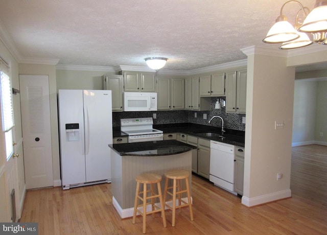 kitchen featuring light wood-style floors, dark countertops, a sink, and white appliances