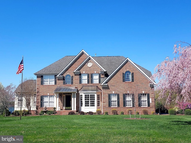 view of front of property featuring brick siding, a shingled roof, and a front lawn