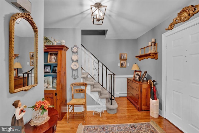 foyer entrance featuring wood finished floors, stairway, and a baseboard heating unit