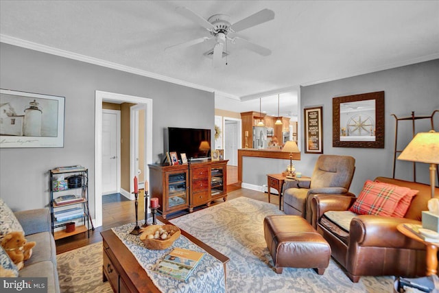 living room with a ceiling fan, ornamental molding, wood finished floors, and baseboards