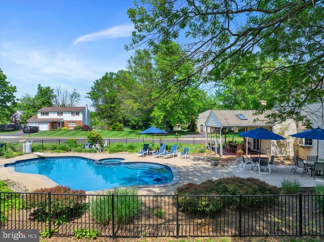 view of pool with fence, a patio, and a pool with connected hot tub