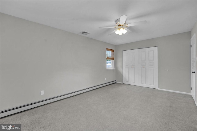 unfurnished bedroom featuring baseboard heating, a closet, carpet, baseboards, and a ceiling fan