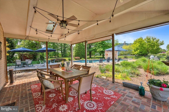 view of patio with outdoor dining space, an outbuilding, a shed, fence, and a ceiling fan