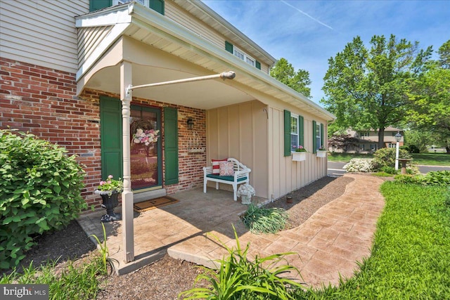 property entrance featuring board and batten siding and brick siding
