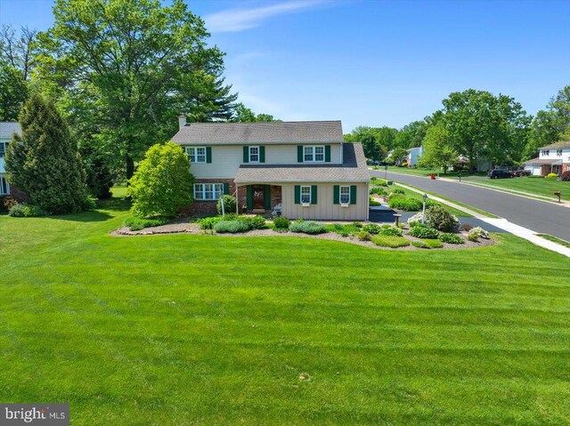 traditional-style home featuring board and batten siding, a front yard, and a porch