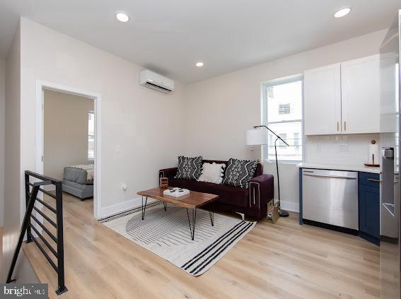 2001 S Norwood St, Philadelphia, PA 19145 - living area featuring light wood-type flooring, a wall mounted AC, baseboards, and recessed lighting