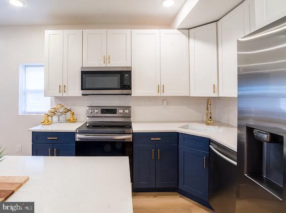 2001 S Norwood St, Philadelphia, PA 19145 - kitchen featuring stainless steel appliances, light countertops, a sink, and blue cabinetry