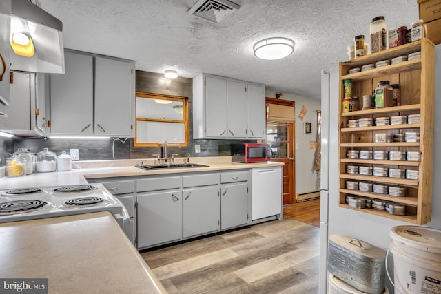 kitchen with visible vents, white dishwasher, extractor fan, light wood-type flooring, and a sink