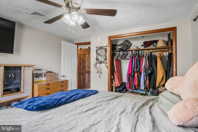 bedroom with ceiling fan, a closet, a textured ceiling, and visible vents