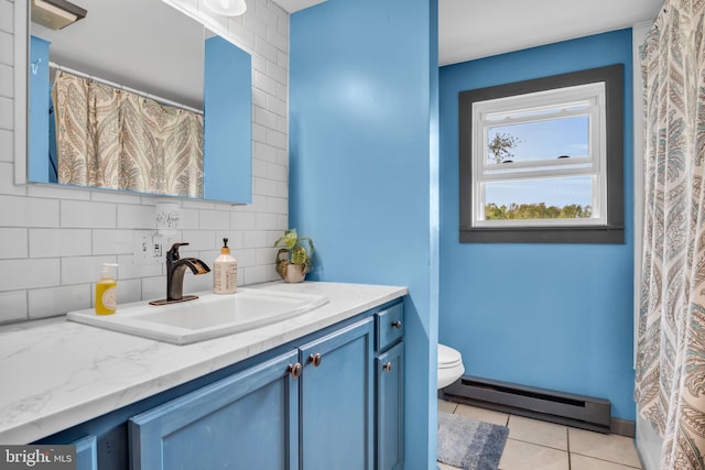 bathroom with tile patterned flooring, decorative backsplash, vanity, toilet, and a baseboard heating unit