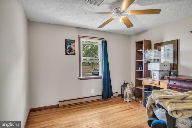 office area featuring a baseboard radiator, light wood-style flooring, a ceiling fan, and a textured ceiling