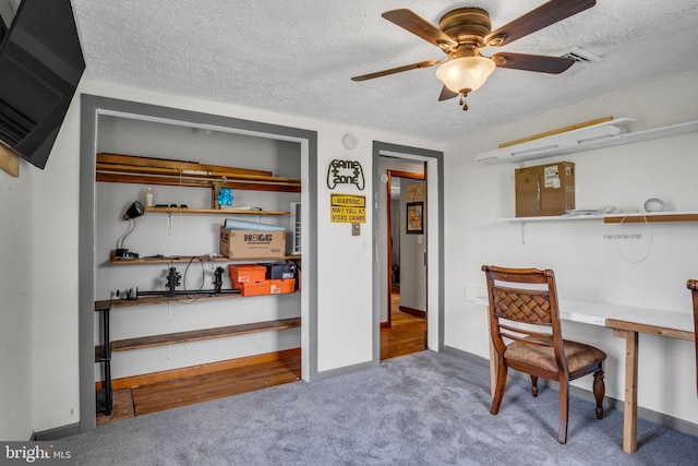 carpeted home office with baseboards, a textured ceiling, and ceiling fan