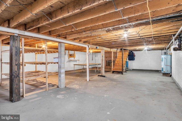 unfinished below grade area featuring stairs, water heater, and concrete block wall
