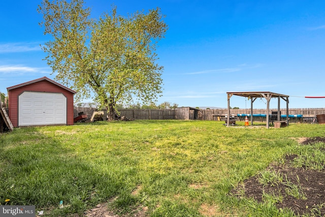 view of yard with an outdoor structure, a fenced backyard, and a detached garage
