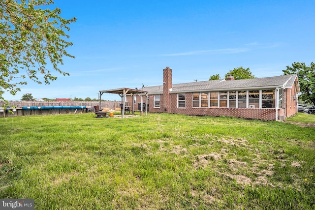 back of house featuring brick siding, fence, a yard, and a chimney