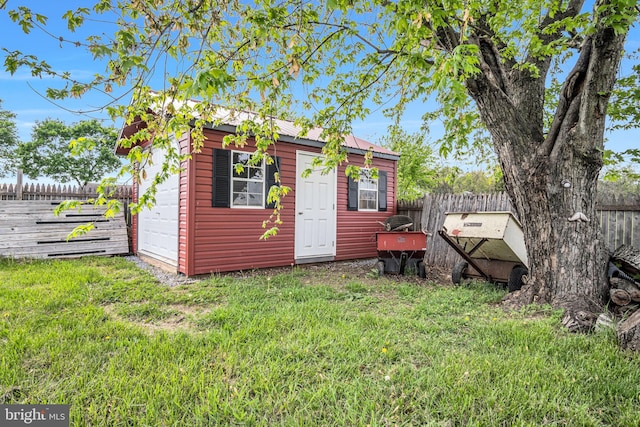 view of outbuilding featuring a garage, a fenced backyard, and an outbuilding