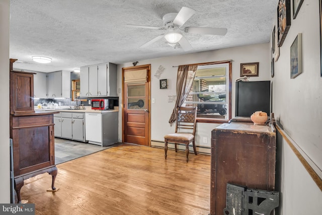 kitchen with light countertops, baseboard heating, a sink, and light wood-type flooring