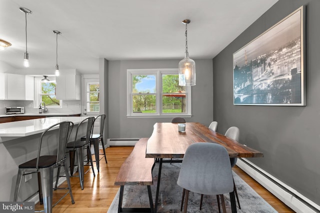 dining room with baseboard heating, a toaster, and light wood-style floors