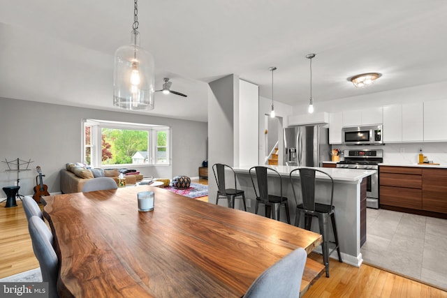 dining space with stairway, ceiling fan, and light wood-type flooring