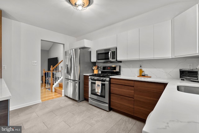 kitchen with backsplash, modern cabinets, white cabinetry, and stainless steel appliances