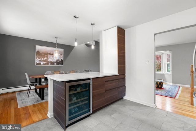 bar with beverage cooler, light wood-type flooring, pendant lighting, and baseboards