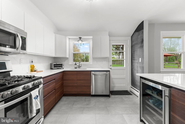 kitchen featuring wine cooler, stainless steel appliances, light countertops, and a sink