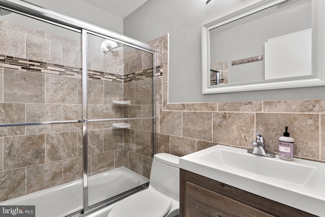 bathroom featuring tile walls, bath / shower combo with glass door, toilet, and vanity