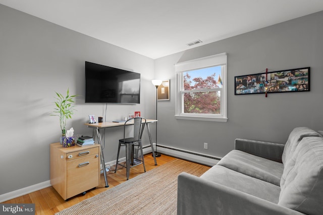 living room featuring baseboard heating, visible vents, light wood-style flooring, and baseboards