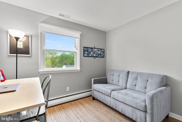 office space with baseboards, visible vents, wood finished floors, and a baseboard radiator