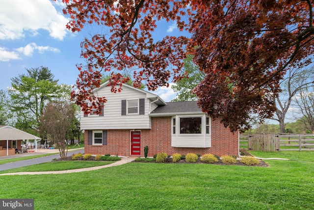 split level home with brick siding, fence, and a front lawn