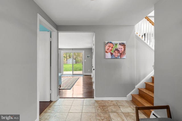 foyer entrance with baseboards, stairway, and light tile patterned flooring