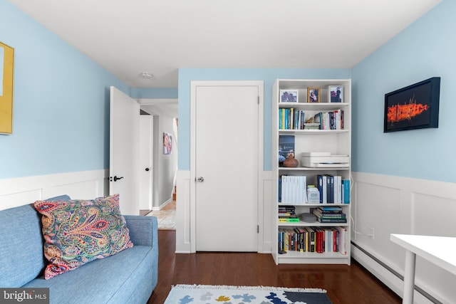 sitting room with wainscoting, wood finished floors, and a baseboard radiator