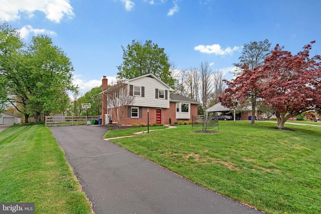 tri-level home featuring a chimney, brick siding, and a front lawn