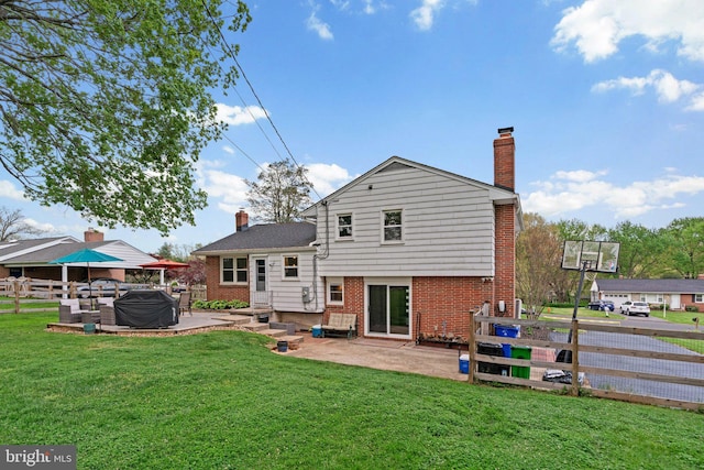 rear view of house featuring a patio, a yard, a chimney, a hot tub, and fence